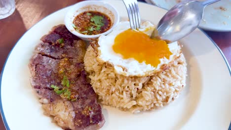yema de huevo cortada en rodajas sobre bistec y arroz