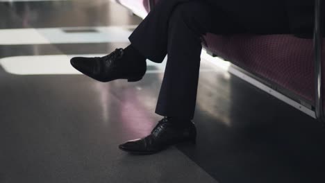 salaryman in a suit sitting on an empty train with his legs cross. - wide shot