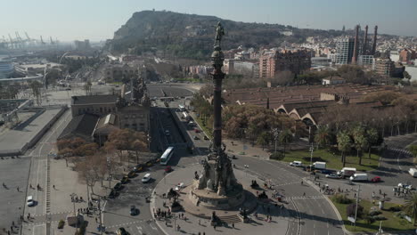 Statue-on-top-of-tall-column-pointing-by-hand.-Fly-over-famous-Columbus-Monument.-Historic-buildings-around.-Barcelona,-Spain