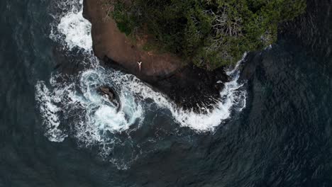 Strong-sea-waves-splashing-and-crashing-on-the-rocky,-green-shoreline-of-Costa-Rica---top-view