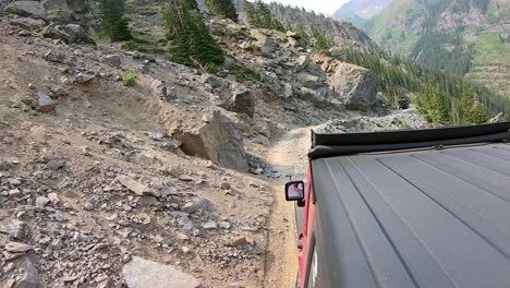 Following-4WD-vehicle-driving-on-Sydney-Loop-trail-cut-into-the-side-of-a-mountain-around-Yankee-Boy-Basin-in-San-Juan-Mountains-in-Colorado