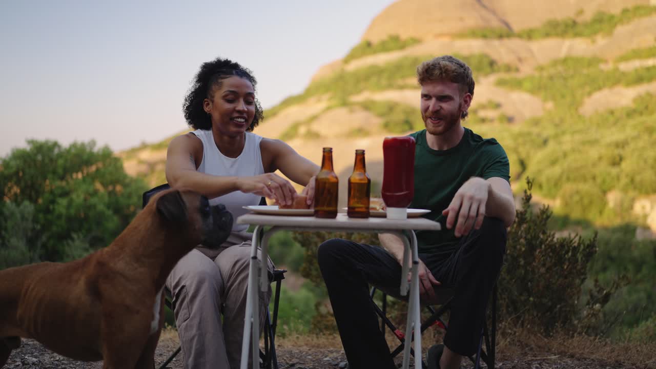 Coppia che si gode un picnic con il proprio cane in montagna