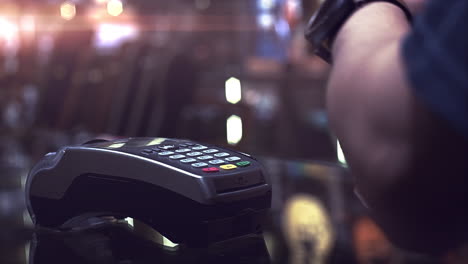 a man using smartwatch to purchase product at the point of sale terminal with near field communication identification technology to complete the transaction