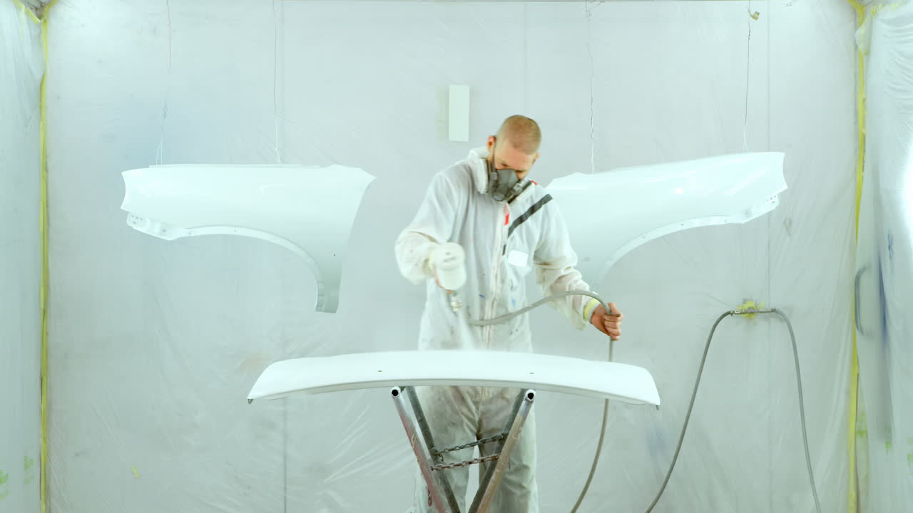 電気噴射銃で車の部品を塗装するメカニック 4k