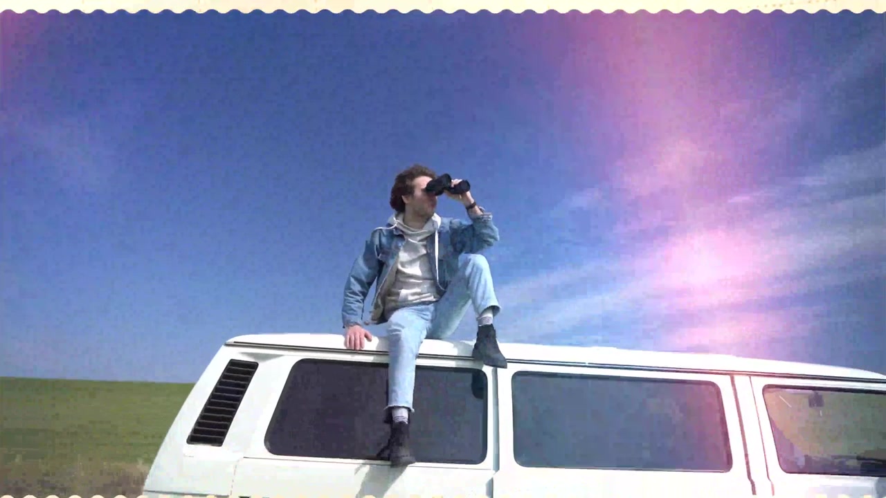 Joven sentado en el techo de una furgoneta mirando a través de binoculares.