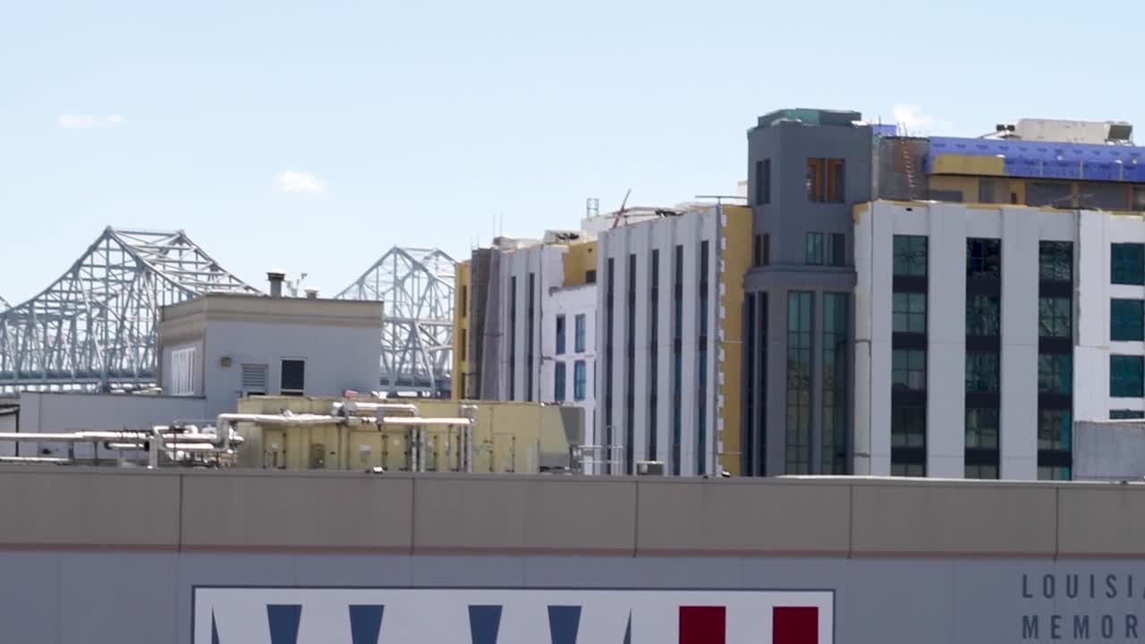 Tilt-up,  Pan right to left, Rooftop Lousiana, Memorial, Pavillian, WWII museum across the rooftops to the Crescent City Connection, bridge, over the Mississippi River.