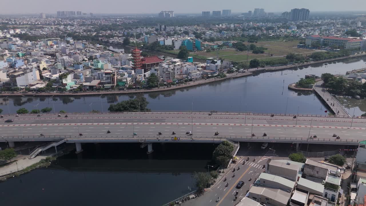 Aerial view of busy freeway over river with urban sprawl on sunny clear day wide static shot