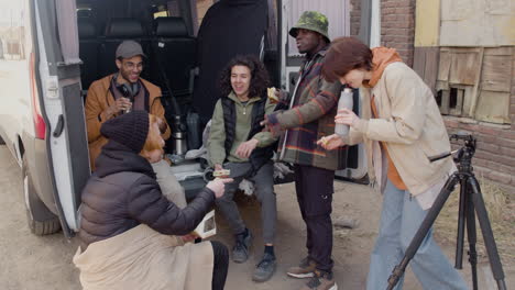 un equipo de producción de películas tomando un descanso mientras come un sándwich y habla detrás de una camioneta en la calle 2