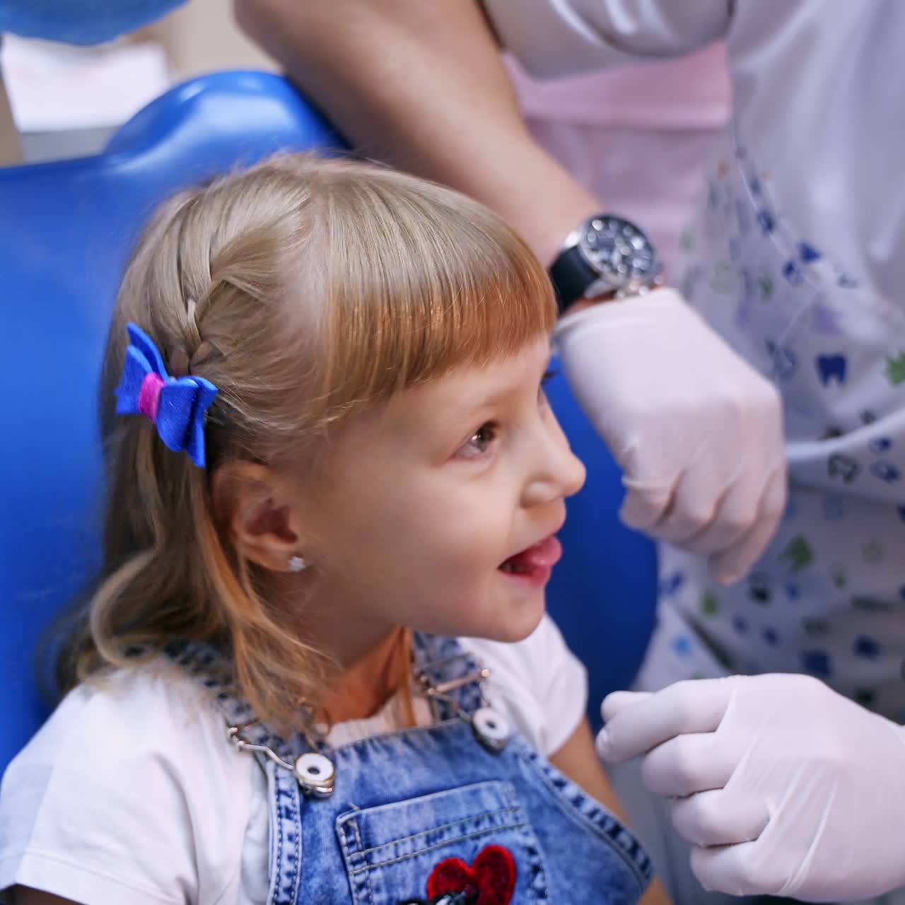 Cute kid at stomatologist office. Pretty little girl sitting in the dentist chair and shows her small tongue. Child dentist's visit.
