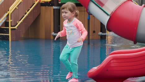 Glückliches-Kleinkindmädchen-Gleitet-In-Zeitlupe-Auf-Dem-Wasserspielplatz-Im-Freien-In-Südkorea-An-Einem-Heißen-Sommertag-Mit-Hoher-Temperatur-Und-Verfolgt-Die-Bewegung