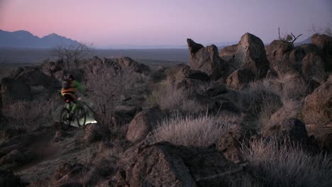 a bicyclist rides through a hilly area at night