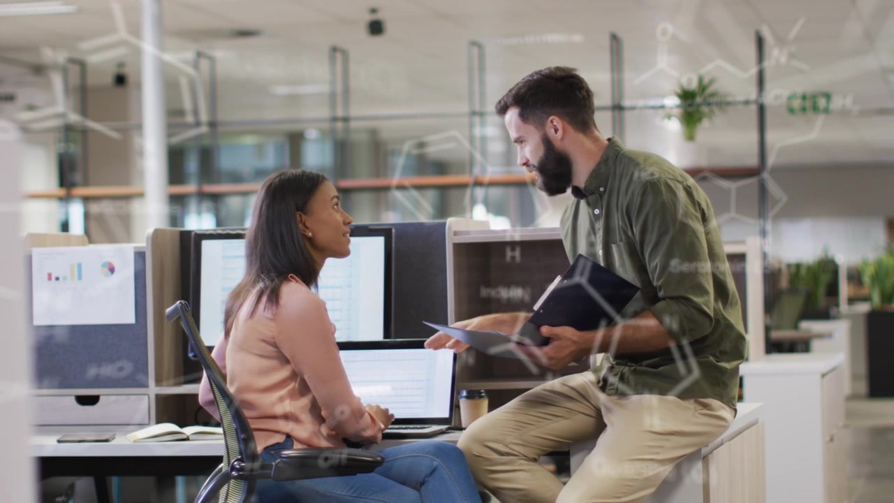 Business team coming perching pointing at laptop collaborating, code overlays over screen