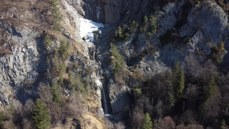 aerial approach of a mountains waterfall with snow on top