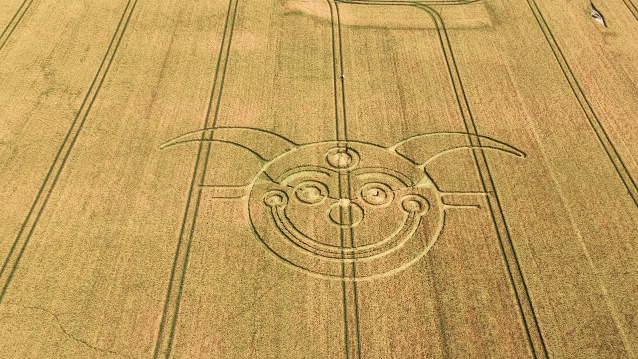 Establishing aerial view of Stonehenge jester crop circle tilt to reveal vast farmland countryside