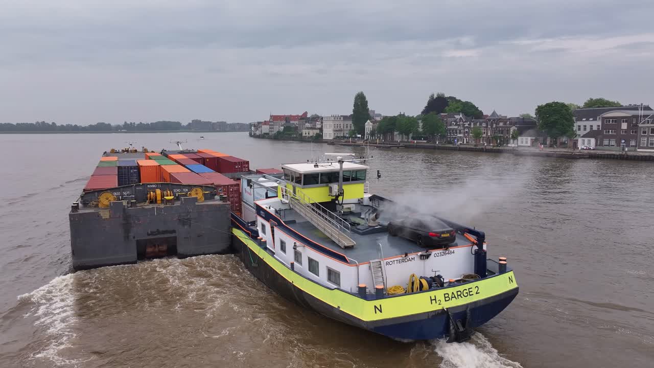 A container barge and an H2 barge navigating a river in Rotterdam