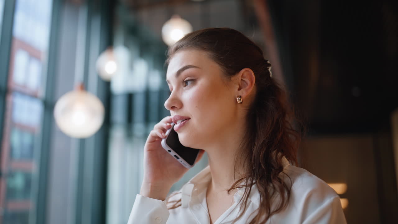 Corporate worker talking mobile phone in modern lobby closeup. Successful woman