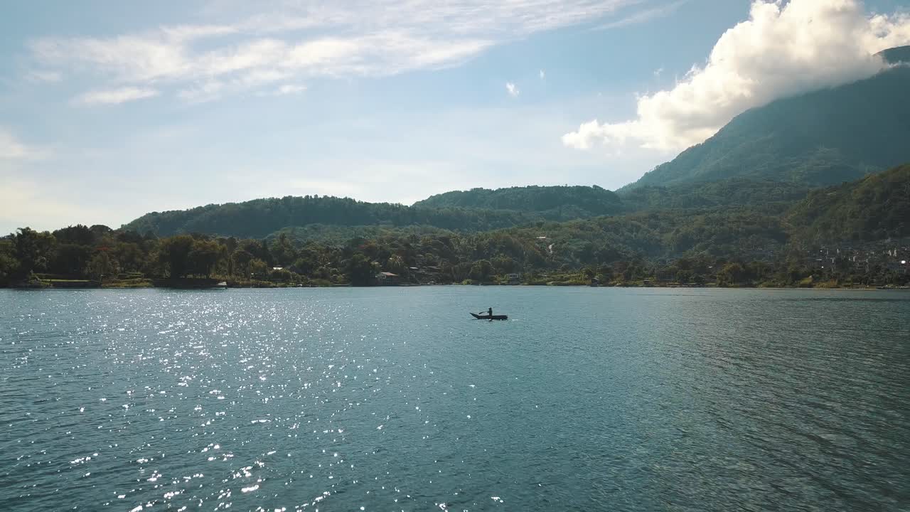 asombrosa antena de drones volando sobre un hombre remando en un bote en el lago de atitlán, guatemala
