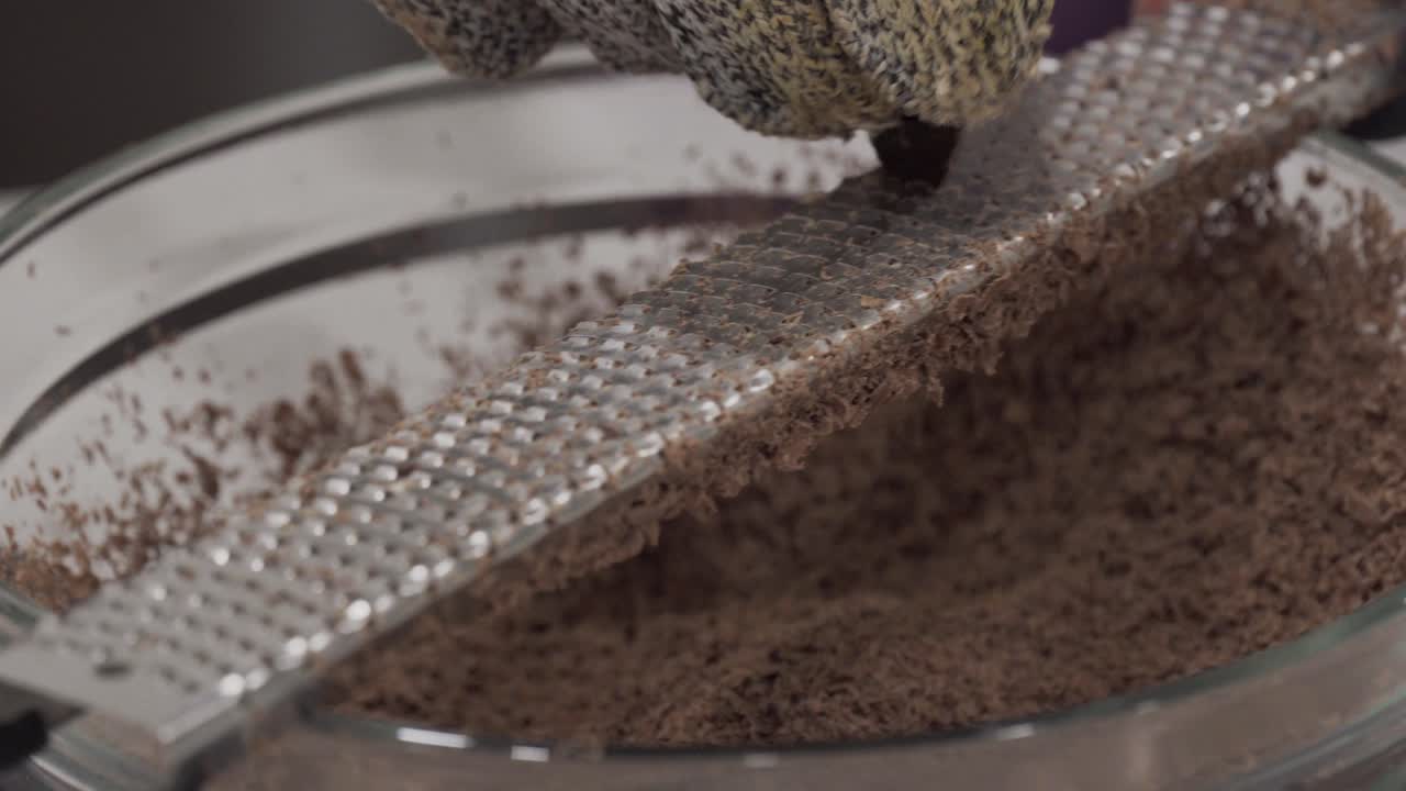 어린 소녀가 안전 장갑을 끼고 백만장자 쇼트브레드 쿠키를 만들면서 녹이기 위해 그릇에 초콜릿을 갈아 넣습니다-3