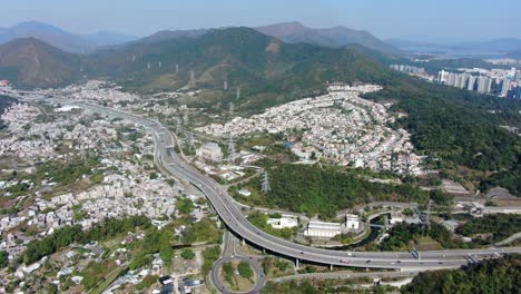 aerial view of hong kong outskirts residential area, with connecting highway and surrounding mountain slopes