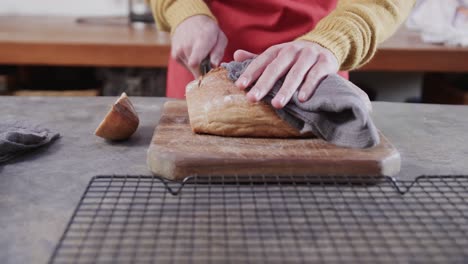 Hands-of-caucasian-man-cutting-bread-in-kitchen,-slow-motion