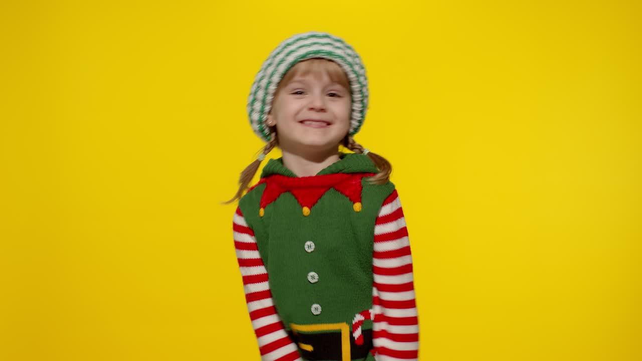 Holčička v kostýmu vánočního elfa, pomocníka Santy, tančící, předvádějící dab tanec, gesto internetového memu.