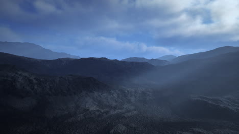 black volcanic dust and mountains with fog in background