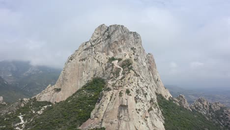drone: crane shot of peña de bernal in querétaro, mexico on a cloudy day