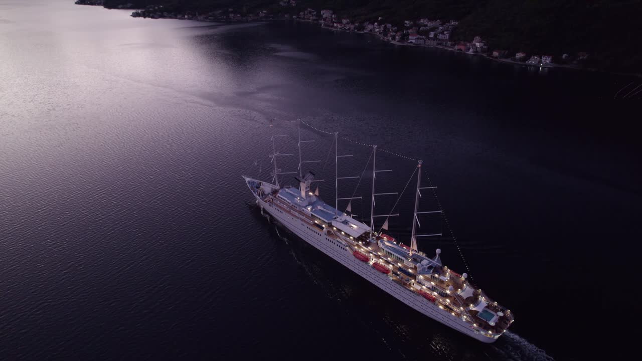 Karadağ, Kotor'da gün doğumu sırasında Kotor Körfezi'nde MSY Wind Surf kruvaziyer gemisinin havadan görünümü, büyüleyici gün doğumu ışığı, sakin atmosfer ve güzel manzaraları sergileyen yüksek kaliteli drone çekimi.