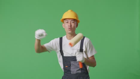 asian man painter wearing safety helmet dancing while standing in the green screen background studio