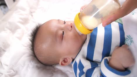 asian baby drinking milk from a bottle, video in 4k