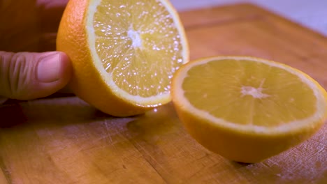 cutting an orange in half on a wooden board