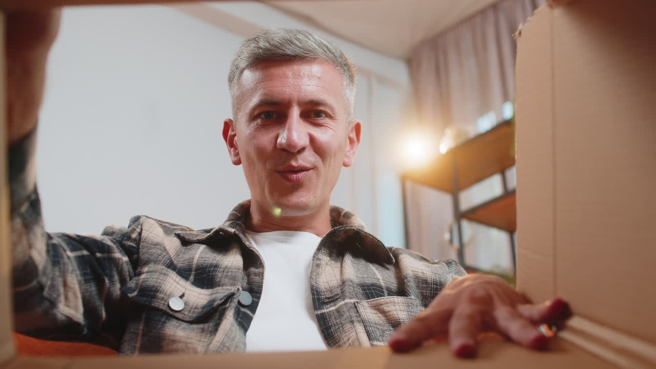 Happy caucasian man shopper unpacking cardboard box delivery parcel online shopping purchase at home