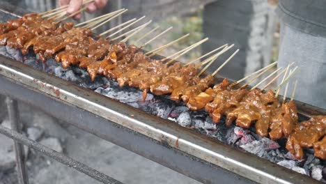 process of cooking chicken satay. grilled chicken over coals.