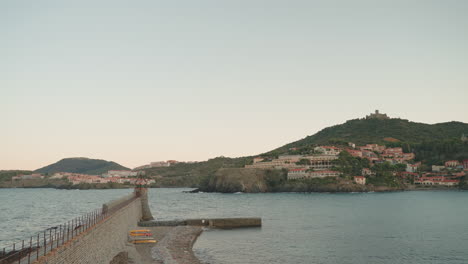 dusk at collioure, lighthouse view, distant fort st elme silhouette, serene sea