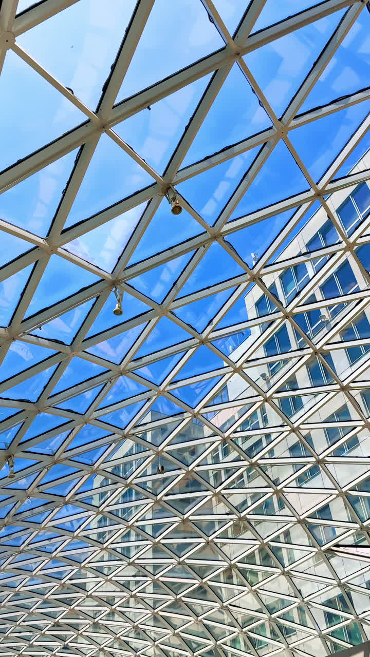 Unique glass design with skyline views. Visitors admire a striking glass and metal design that frames the blue sky above, enhancing the urban landscape below