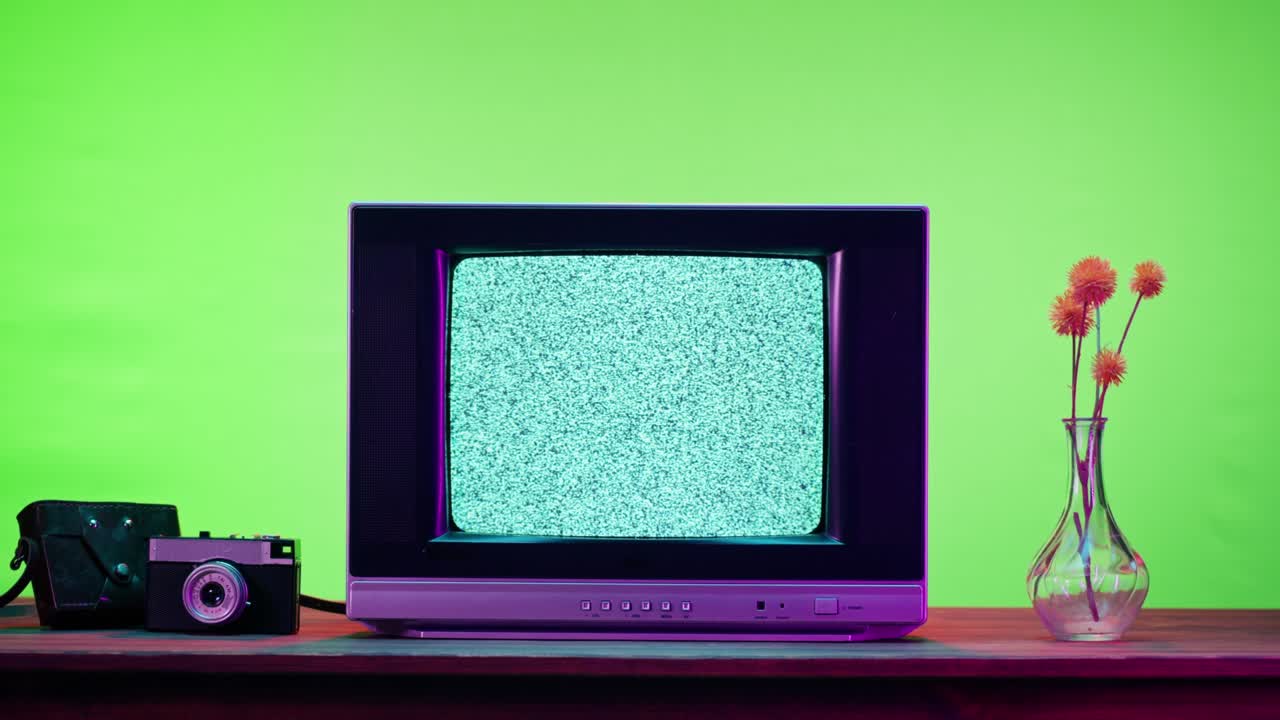 Old television with grey screen on chroma green background. Close-up of vintage tv on table with retro photo cameras, nostalgia