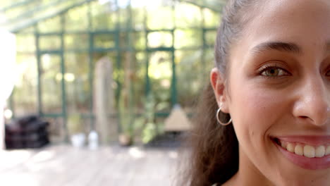 smiling woman with hoop earring in glass house, enjoying peaceful yoga session, copy space