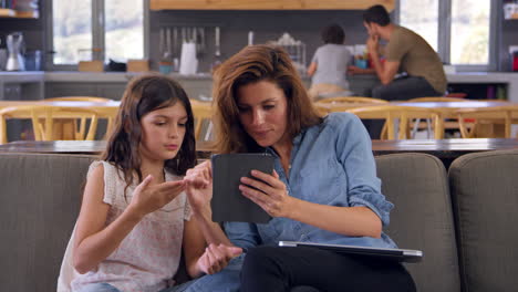 Mother-And-Daughter-Sitting-On-Lounge-Sofa-Using-Digital-Devices