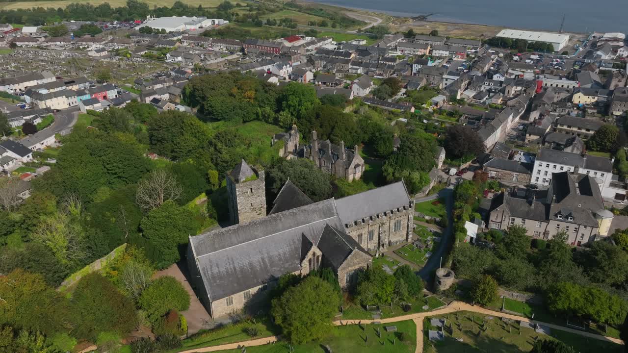 St. Mary's Collegiate Church, Youghal, County Cork, Ireland, September 2024. Drone orbits counter clockwise showcasing the graveyard facing facade of the religious building above the river side town.