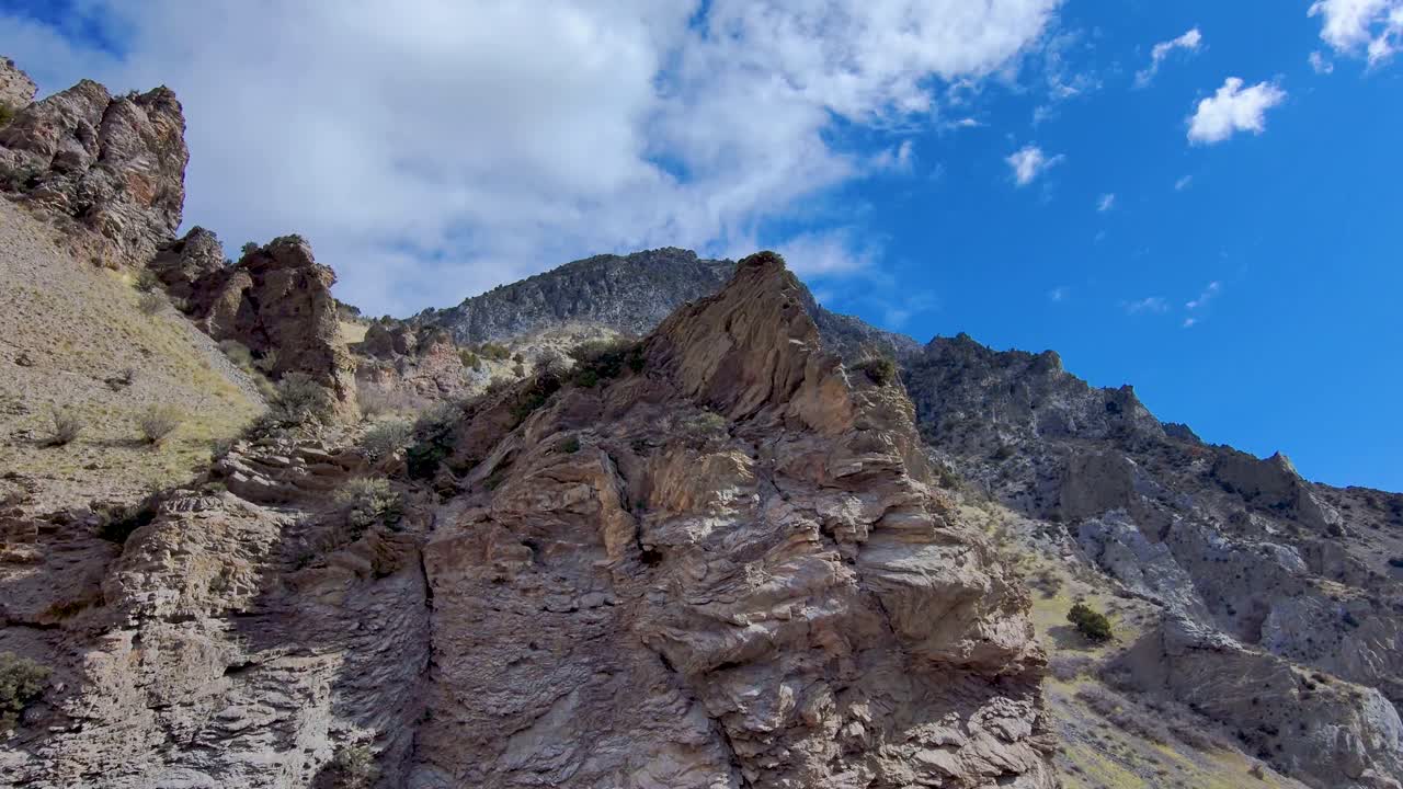 vista de un pico de montaña irregular que luego vuela hacia atrás para revelar el terreno accidentado de acantilados, picos y estratos geológicos en las montañas rocosas