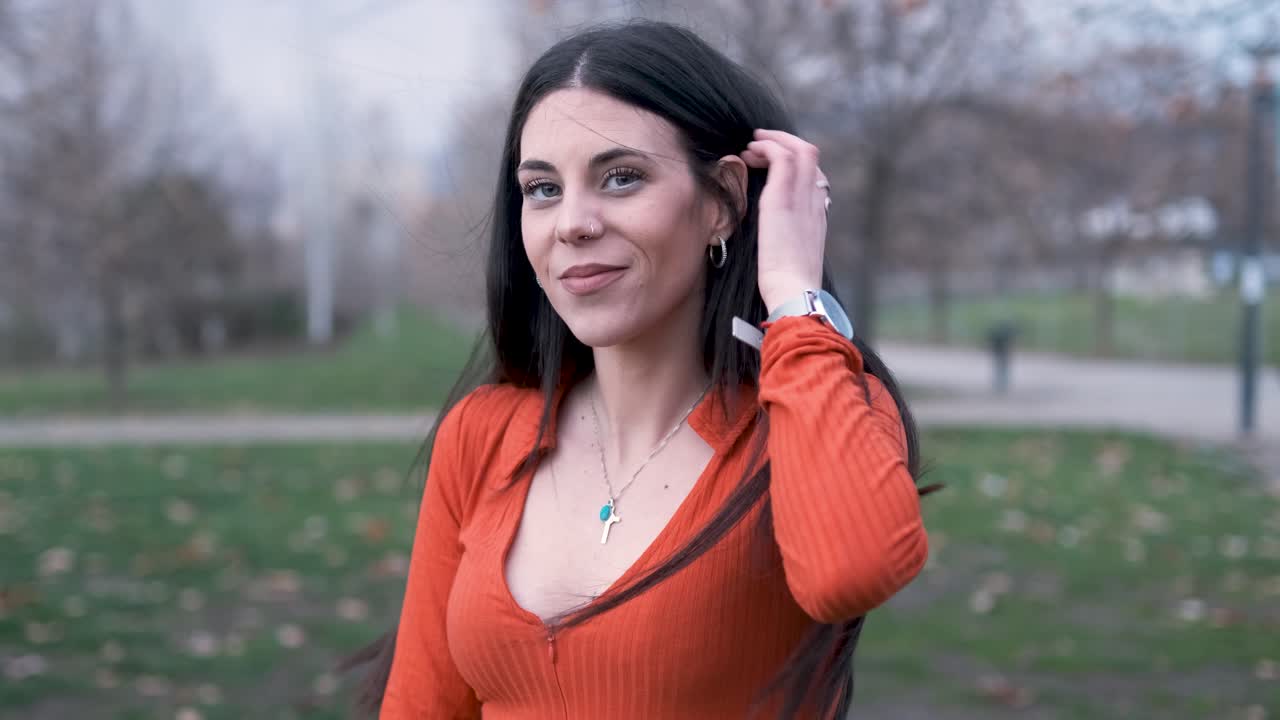 Young woman looking at the camera and smile while standing outdoors in the park