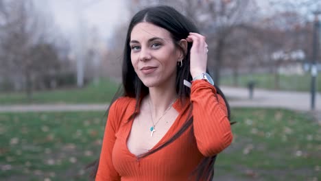 young woman looking at the camera and smile while standing outdoors in the park