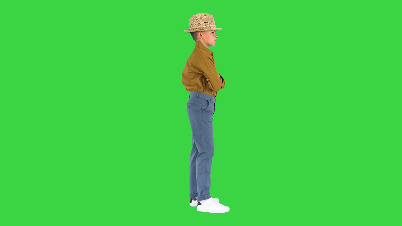 셔츠와  모자를 입은 소년은 팔을 고 팔을 허지에 놓고 녹색 스크린, 크로마 키에