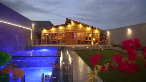 Aerial-pan-left-shot-of-house-with-lighting-decor,-unrecognizable-man-on-swing