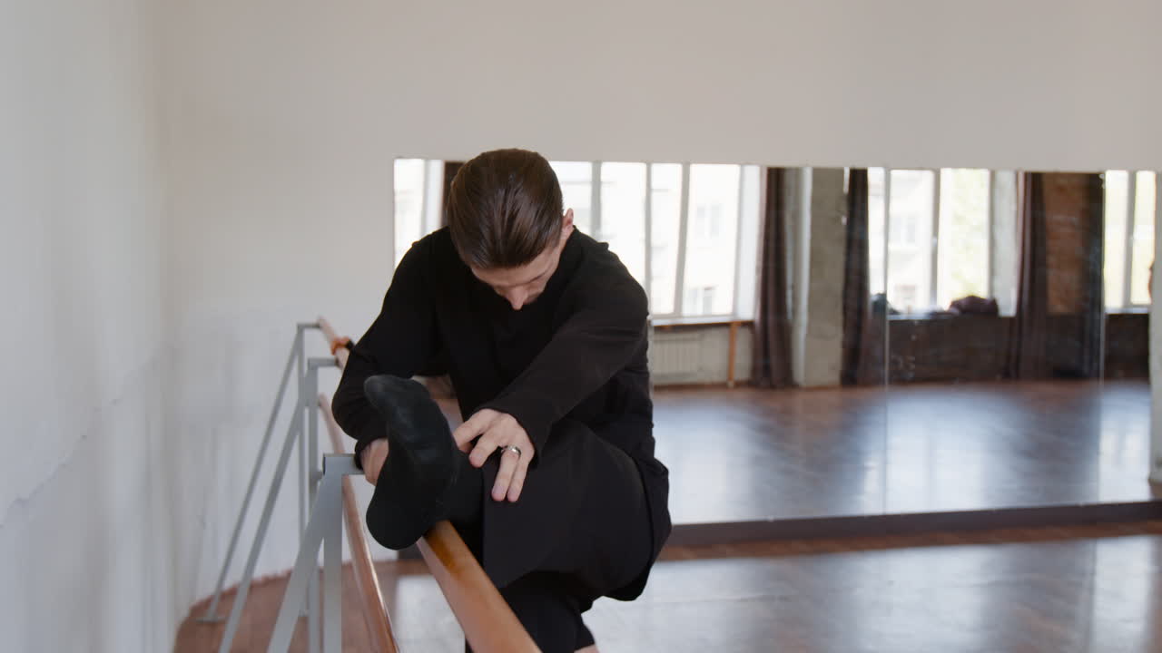 Male Dancer Stretching at Ballet Barre in a Studio
