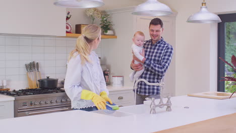 father and baby son watch as mother wash dishes in sink - shot in slow motion