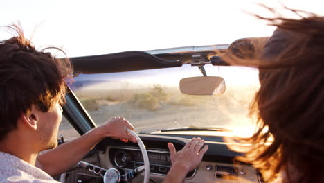 una pareja blanca en un coche abierto gestando, vista de atrás, de cerca
