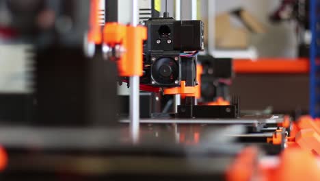 a collection of three 3d printers shows them all printing, the camera racks focus from the middle printer to the closest one