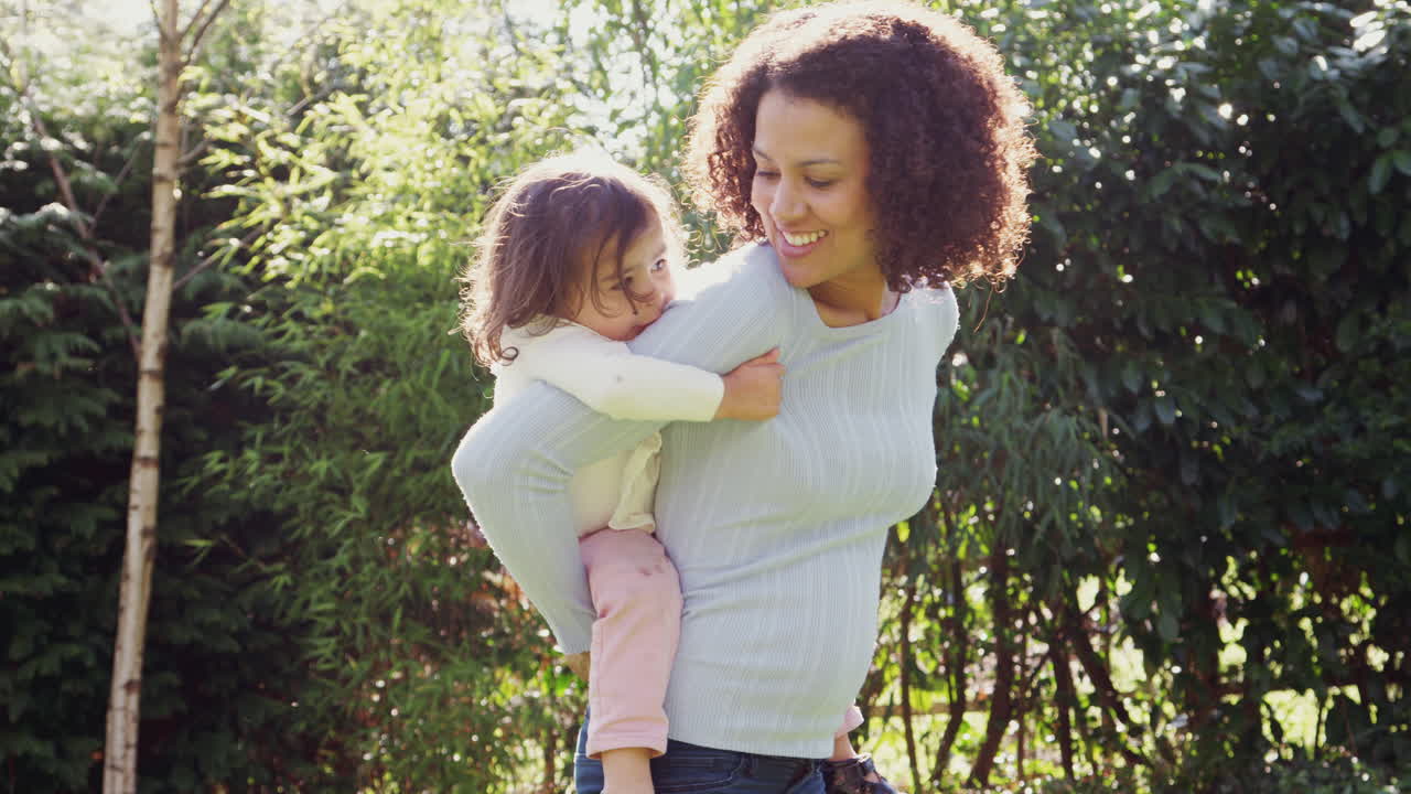 madre dando a su hija un paseo en el jardín en casa
