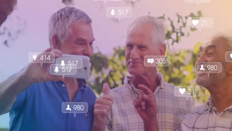 Animation-of-media-icons-over-happy-senior-diverse-men-using-smartphone